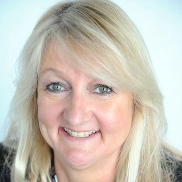 Smiling blonde woman with light background.
