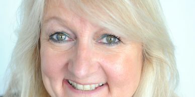 Smiling woman with blonde hair and blue eyes.