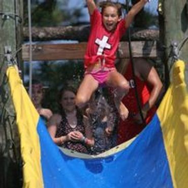 A young girl jumps into a splash of water during outdoor fun.