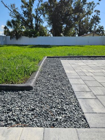 Concrete curbing along grass and rocks and pavers.