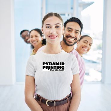 Smiling diverse group posing with Pyramid Printing logo on front woman's shirt.