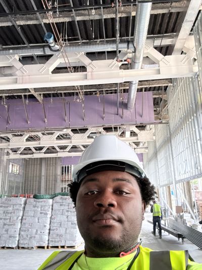 Worker wearing hard hat and safety vest in a construction site.