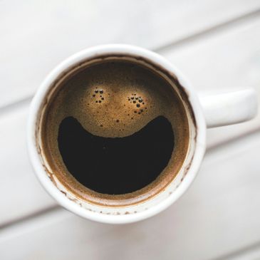 Coffee in a cup with foam forming a smiley face.