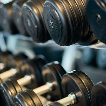 Close-up of stacked black dumbbells in a gym rack.