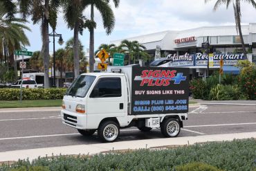 A small truck with an advertising sign for Signs Plus.