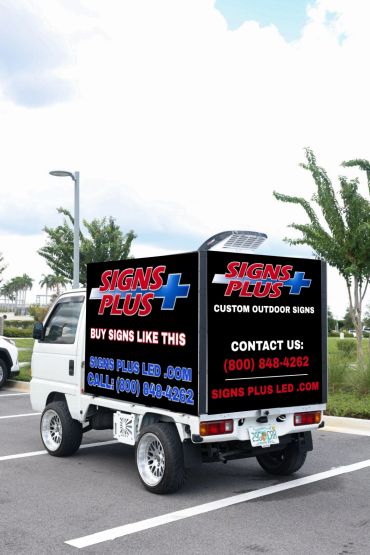 Small truck with Signs Plus outdoor advertising signs.
