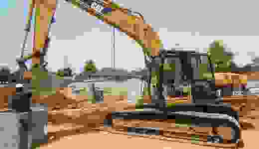 Caterpillar CAT 320CL hydraulic excavator working on  a job site lifting a concrete pipe.