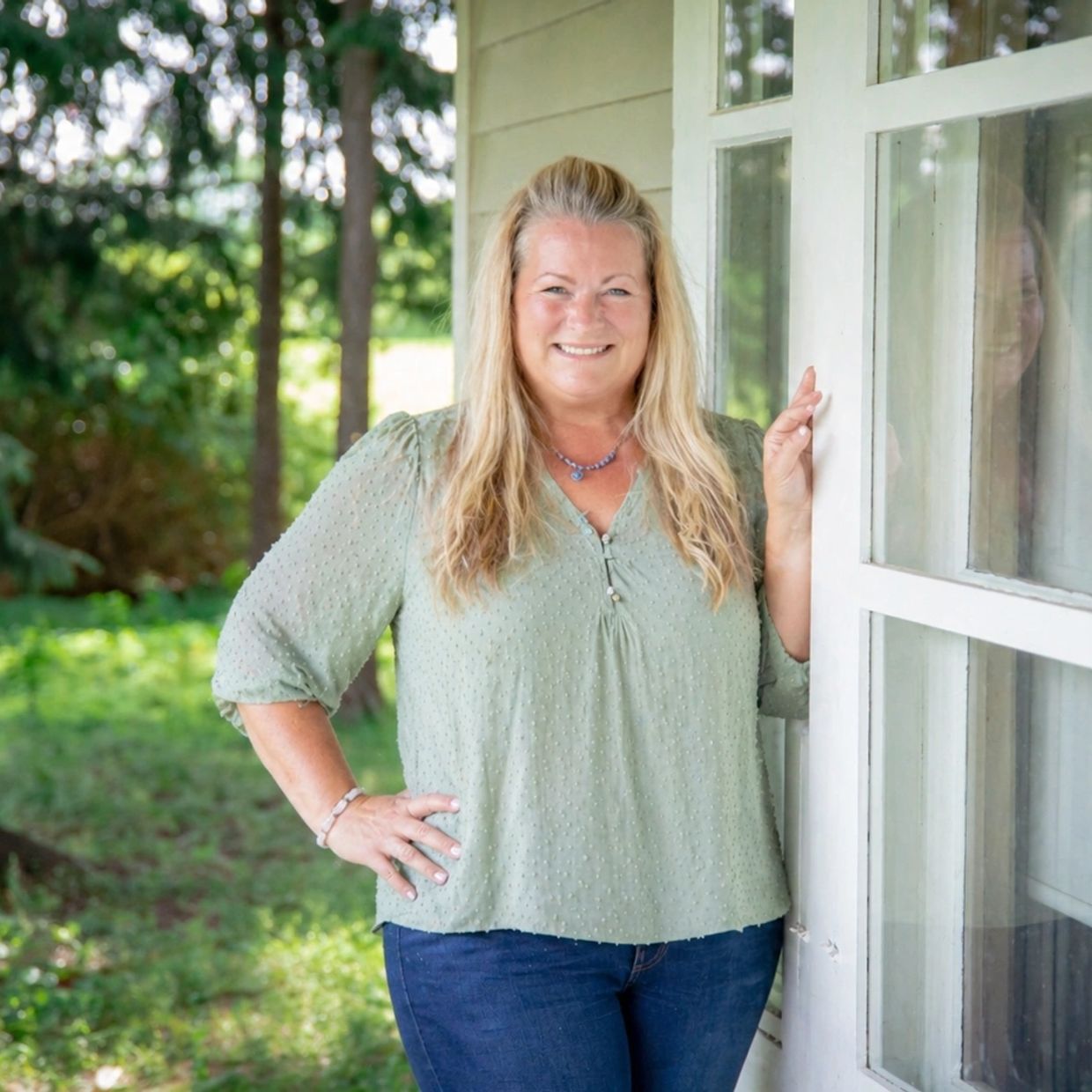 Smiling woman standing by a window outdoors.