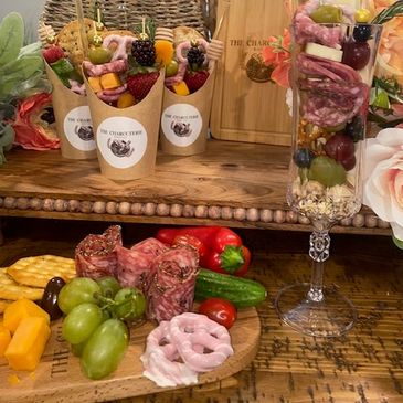 Elegant charcuterie cups and platter with meats, fruits, and cheese.