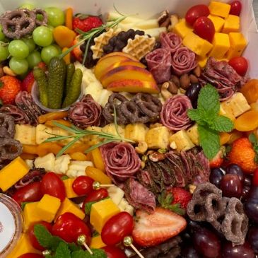 Colorful charcuterie board with fruits, meats, and cheese.