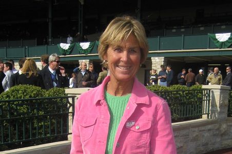 Woman in pink jacket smiling outdoors.