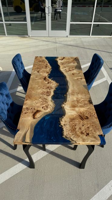 Elegant wooden river table with blue resin and four blue velvet chairs.