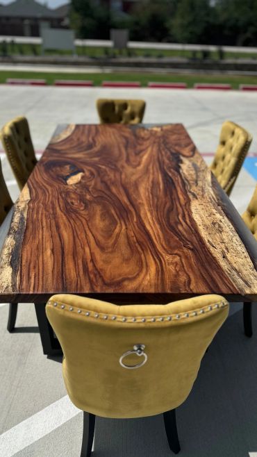 Rustic wooden table with yellow upholstered chairs outdoors.