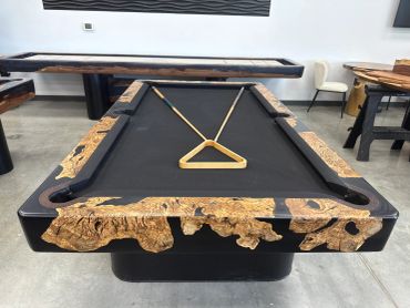 A stylish black pool table with natural wood accents and pool cues arranged in a triangle.
