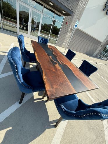 Elegant wooden table with blue velvet chairs set outdoors in a parking lot.