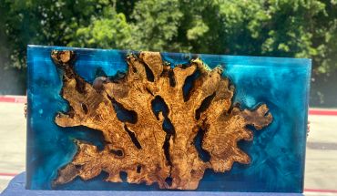 Epoxy resin table with natural wood centerpiece and blue translucent edges.
