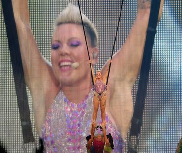 Female singer and actor Pink gets ready to fly through the air suspended on a harness.