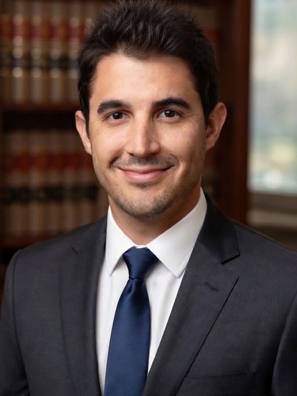 Professional man in suit and tie smiling in an office setting.