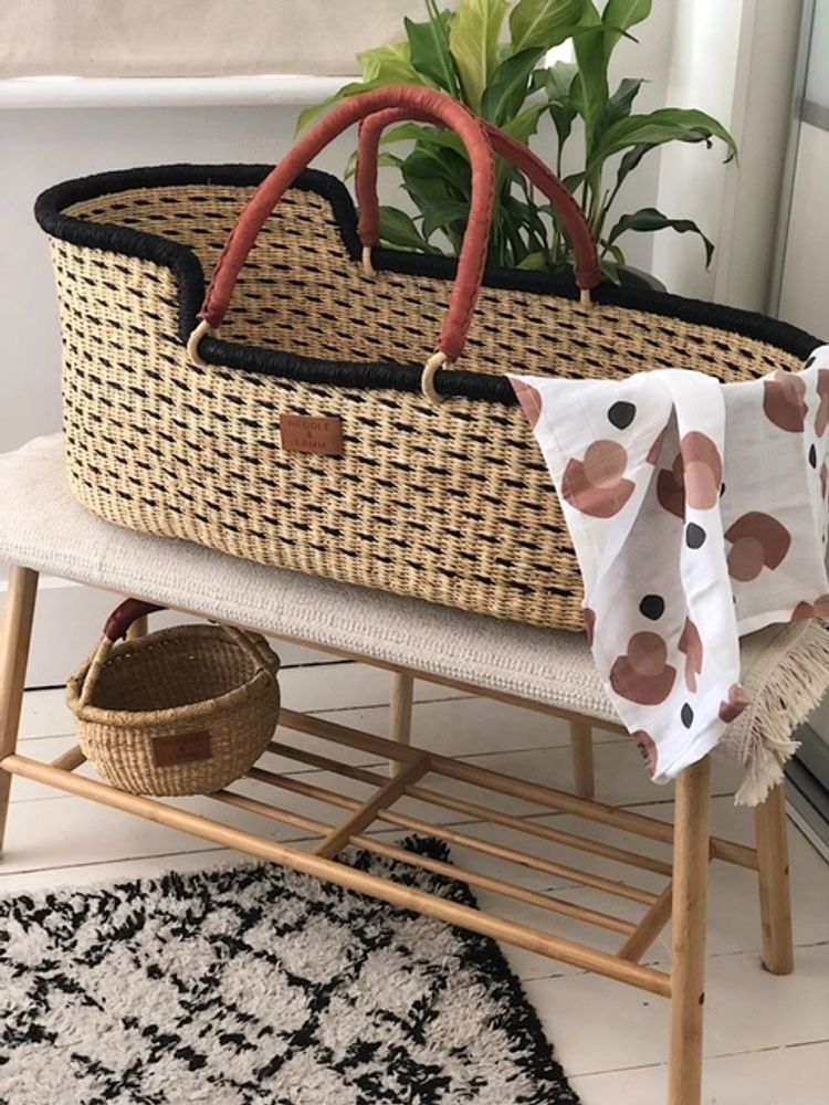 Kobi Moses Basket on table with organic draped muslin. Kandigo Mini Bolga Basket under the table.