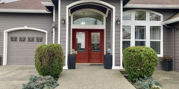 Modern house entrance with red double doors and symmetrical shrubs.