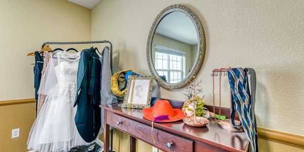 Dressing area with wedding dress, suits, and accessories on a rack and table.