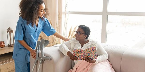 A nurse comforting a woman with crutches sitting on a couch.