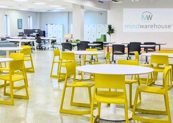 Open space work space at mindwarehouse with white tables and yellow chairs.