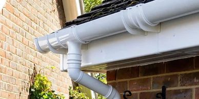 White rain gutter system installed on a brick house corner.