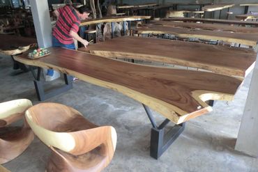 Decor Direct fabricator inspecting a row of live edge slab dining tables being built in a warehouse