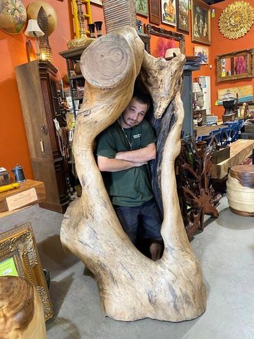 Decor Direct team member standing inside a massive 7 foot tall wood log art sculpture