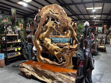 Round live edge slab art piece mounted on iron stand in warehouse