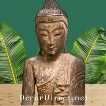 Buddha wood carving sculpture shown with tropical plants in garden or patio background