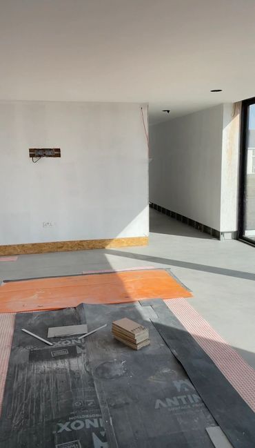 Room under construction with materials on the floor and sunlight streaming in.