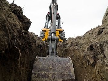A Backhoe digging and Excavating a trench