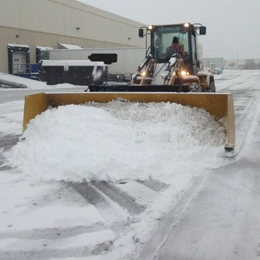 Loader with a pusher box removing snow during a snowstorm