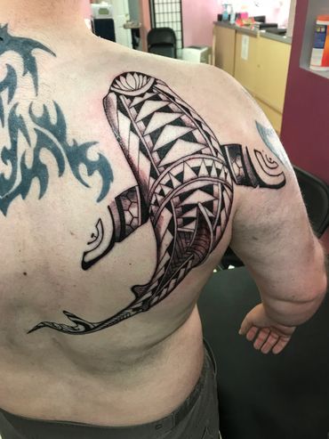 Intricate tribal-style shark tattoo on a man's back.