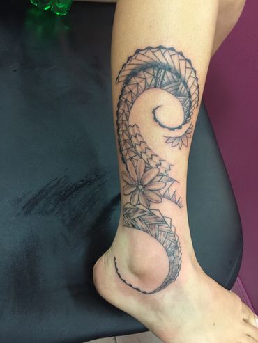 Intricate spiral tattoo with floral and geometric patterns on leg.