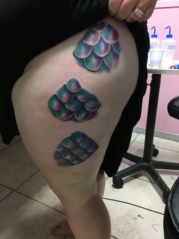Colorful fish scale tattoos on thigh.