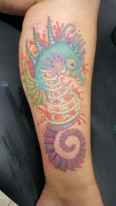 Colorful seahorse tattoo on a forearm.