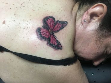 Red and black butterfly tattoo on shoulder.