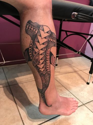 Tribal patterned tattoo of an animal on a person's leg.