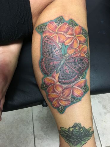 Tattoo of butterfly and flowers on a leg.