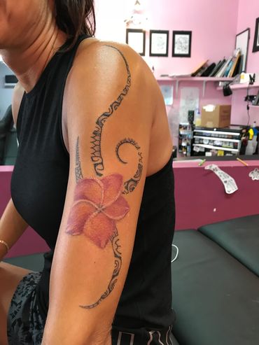Close-up of a shoulder tattoo with floral and tribal designs.