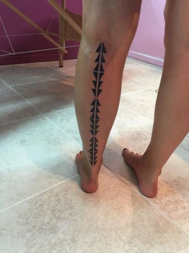Geometric arrow tattoo on calf.