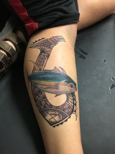 Tattoo of a fish and tribal design on a leg.