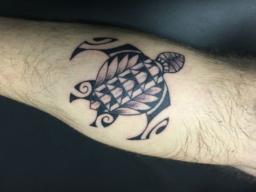 Black tribal turtle tattoo on a leg.