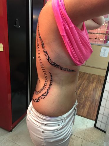 Side view of a tribal tattoo on a person's torso.