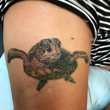Realistic sea turtle tattoo on skin.