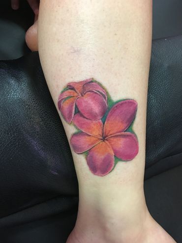 Colorful tattoo of a pink flower on a calf.
