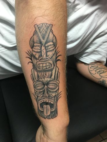 Tiki-style tattoo on forearm.